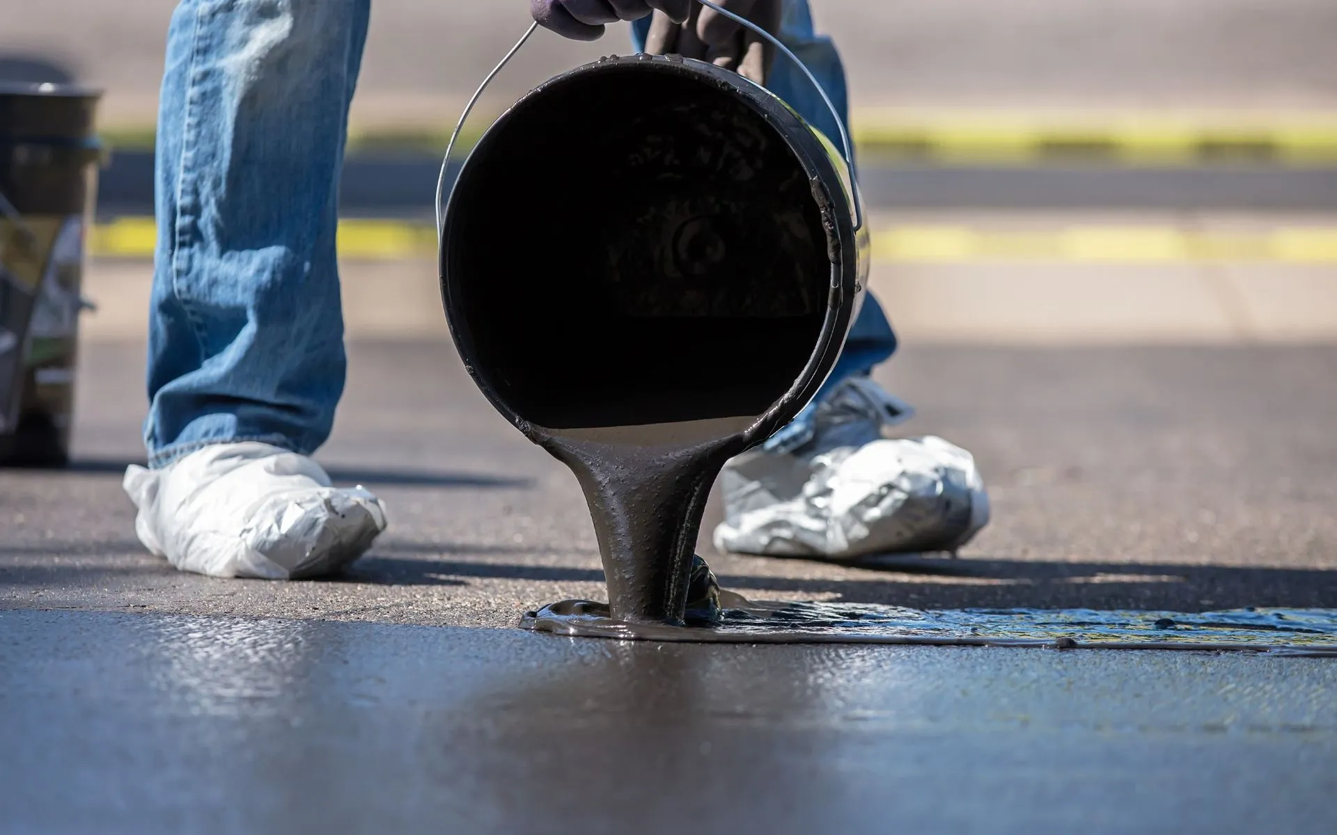 local contractor pouring quality sealant over asphalt driveway