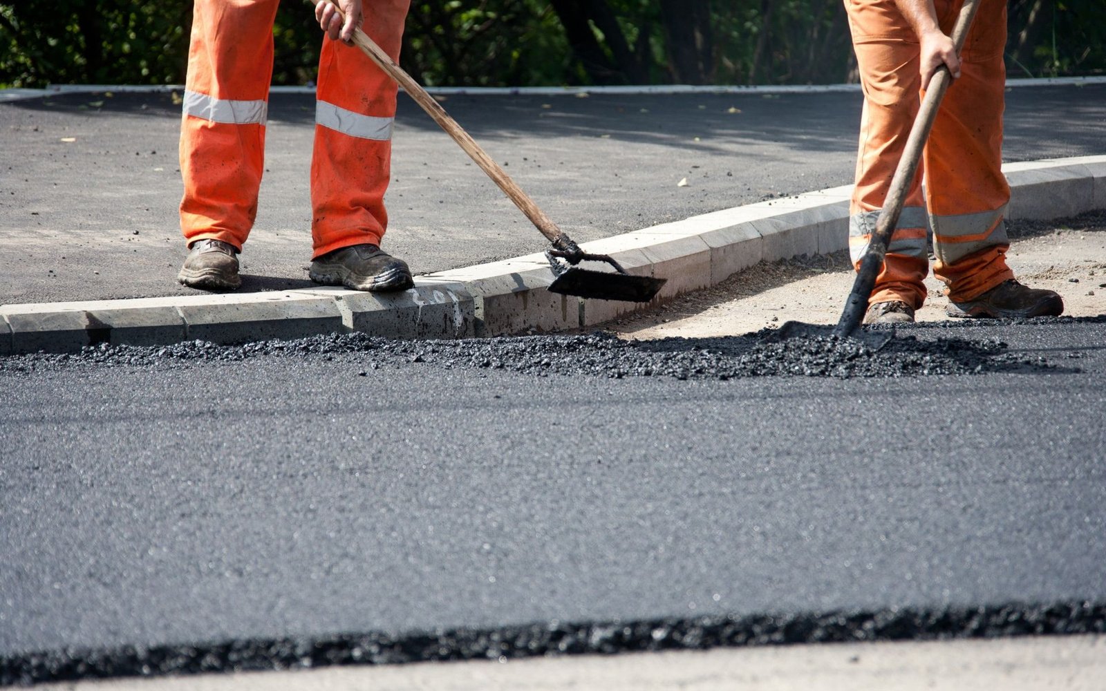 asphalt contractors spreading the asphalt mix over the base material