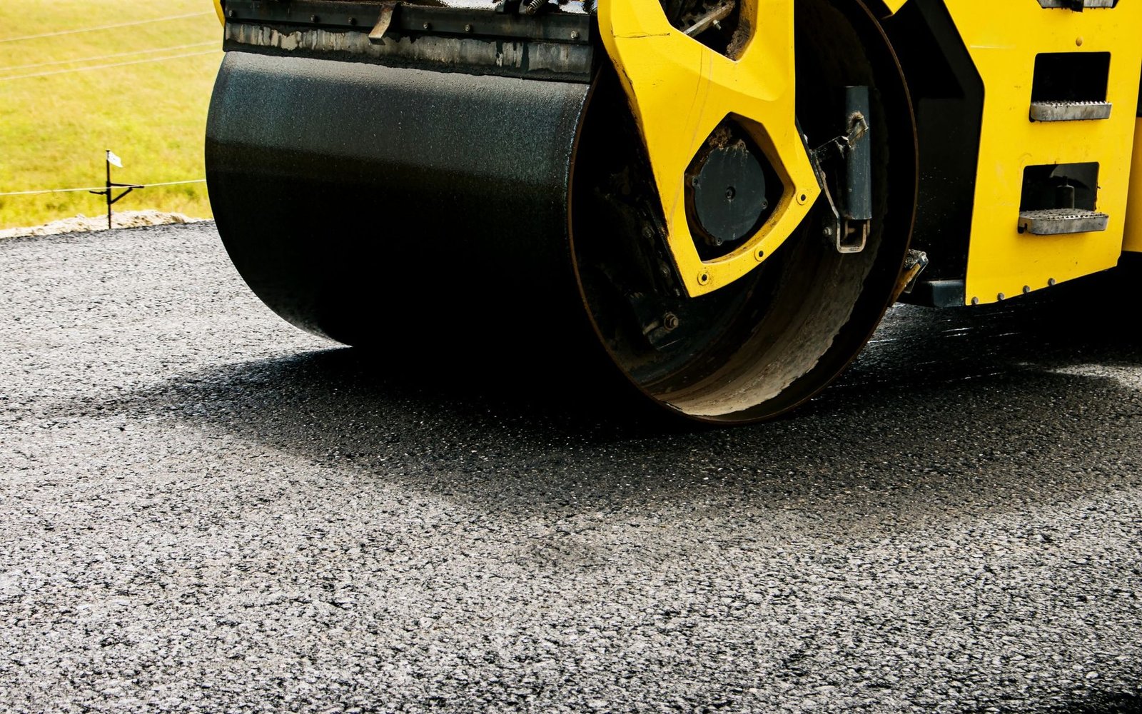 a road roller is operated to compact the newly paved road